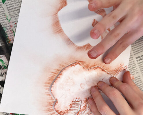 Gepresste Zeichenkreide wird verwischt - Schablonen im Kunstunterricht