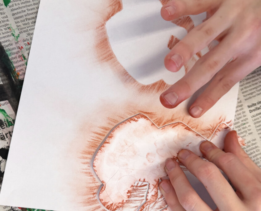 Gepresste Zeichenkreide wird verwischt - Schablonen im Kunstunterricht